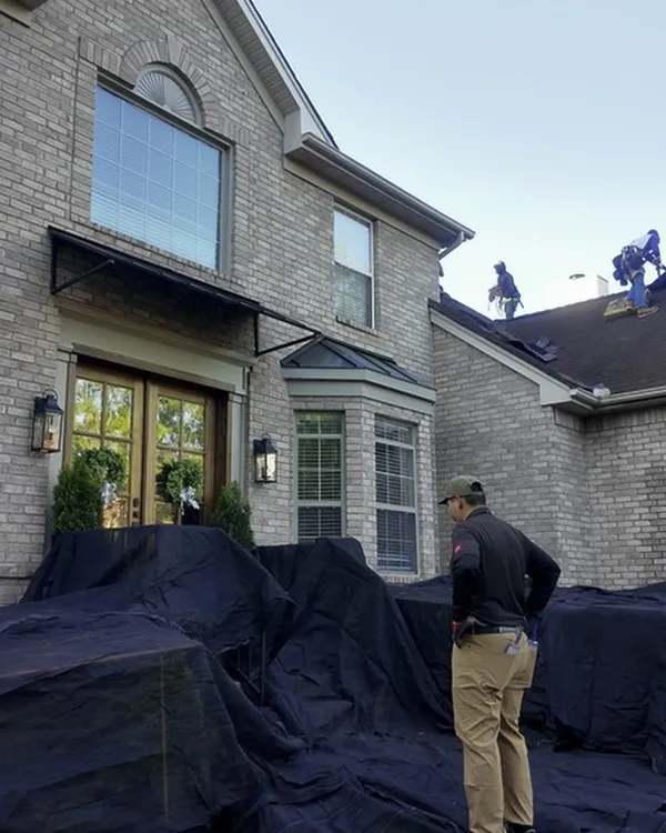 A Hisway team member on the tarps in front of the home while the crew works on the roof