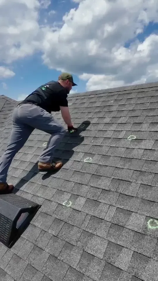 A Hisway team member circling hail hits on shingles in green chalk