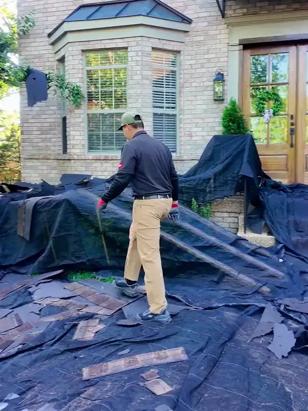The crew picking up old shingles from the tarps while the project manager watches